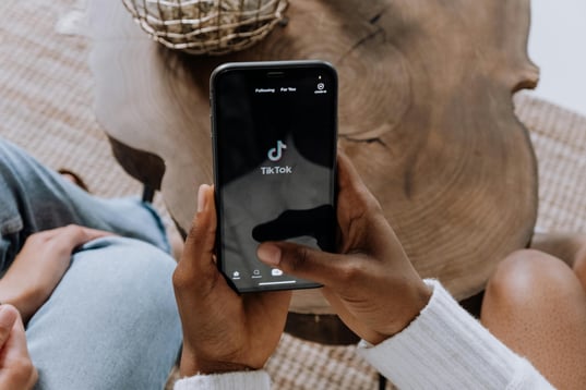 A person holding a smartphone with the TikTok app open. 